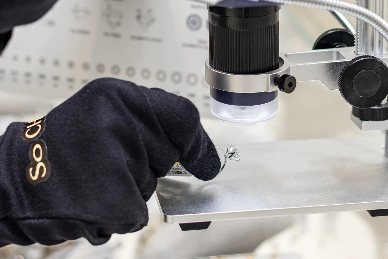 Gloved hands inspecting a gemstone with a digital microscope