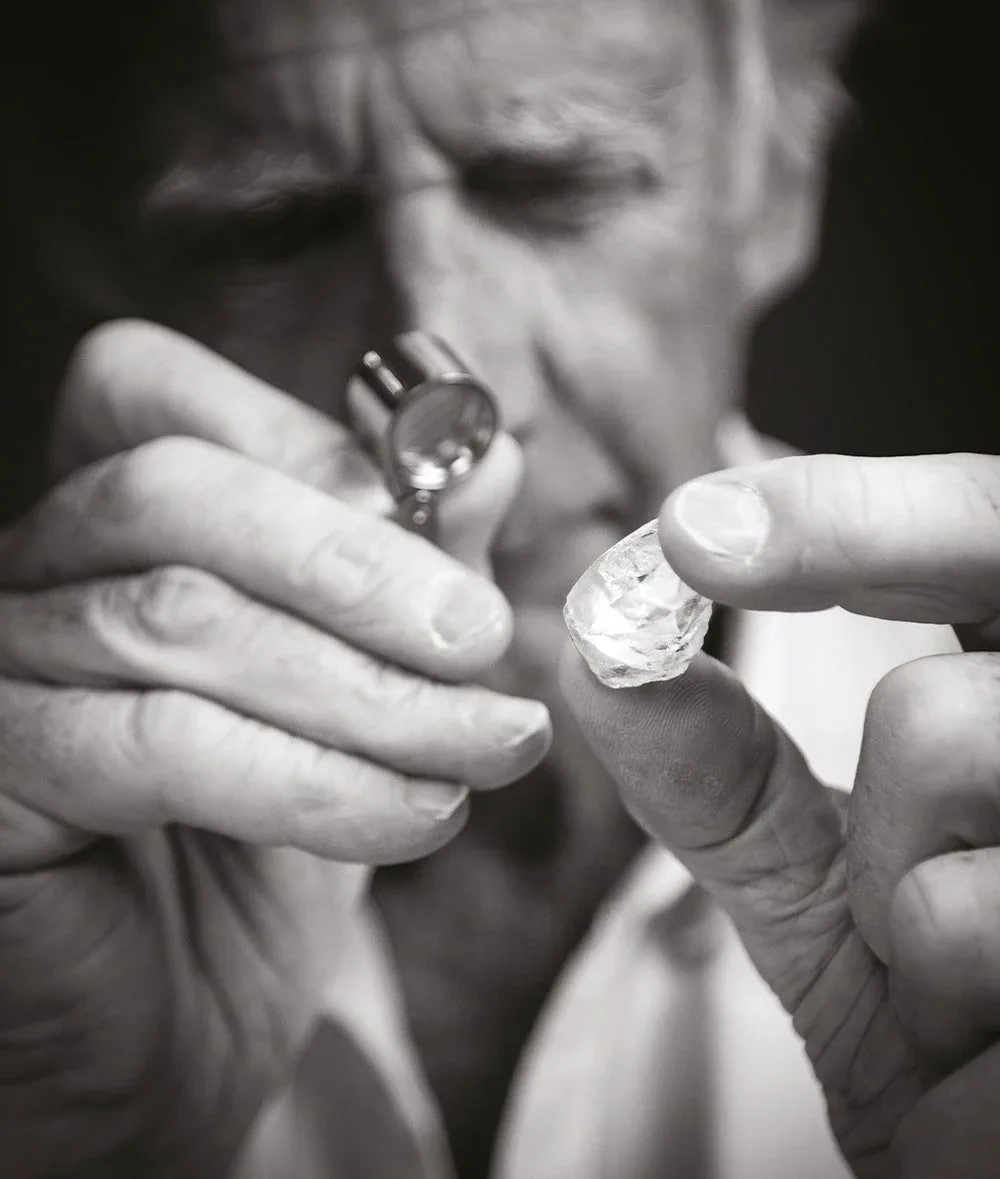 A gemologist examining a rough gemstone with a loupe