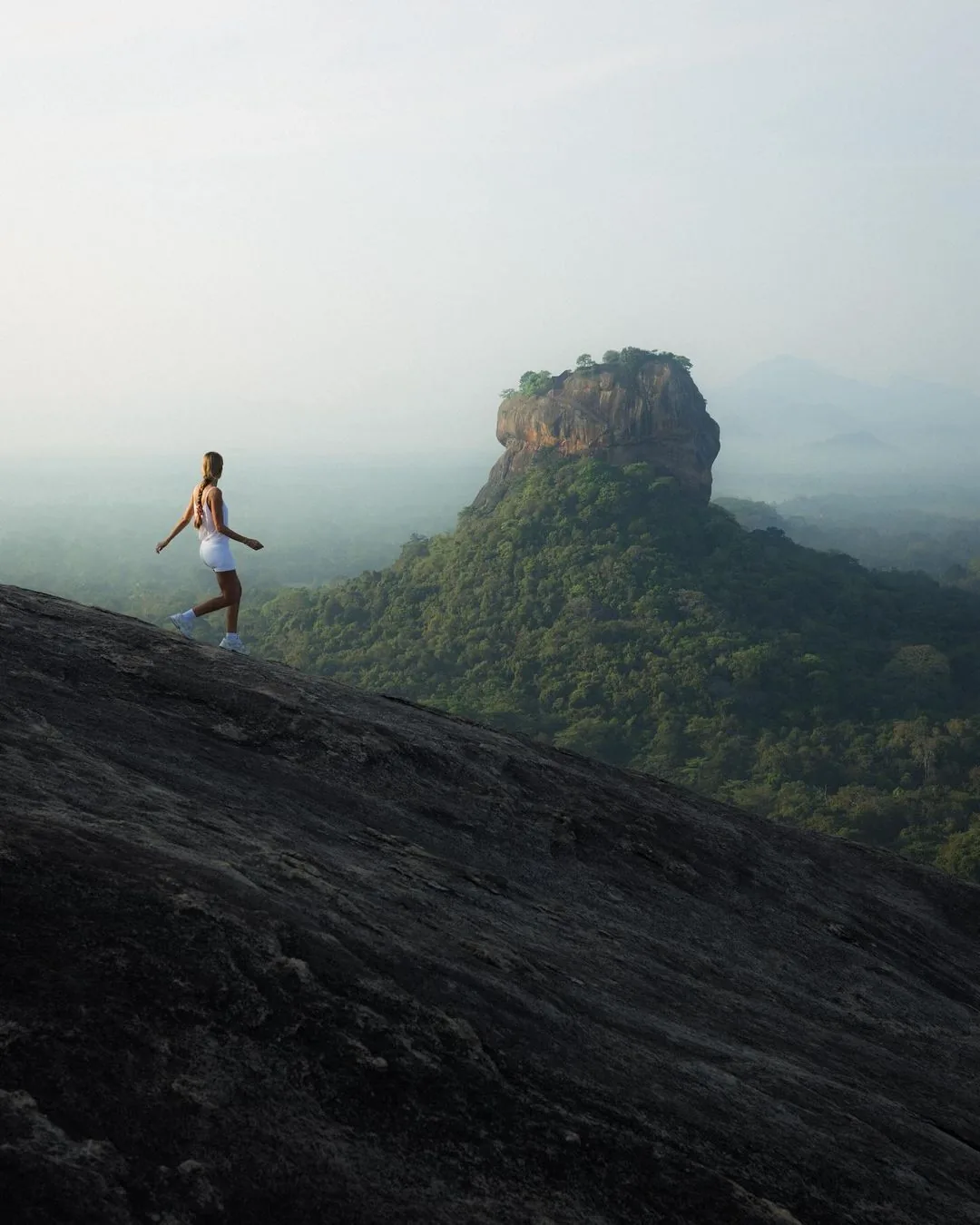 A traveller hiking with Sigiriya rock fortress in the distance