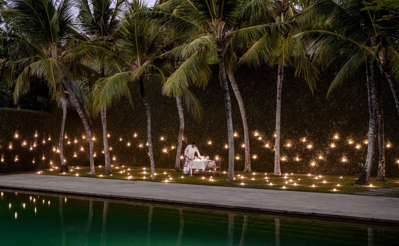 A candlelit private dining setting beside Amangalla’s pool