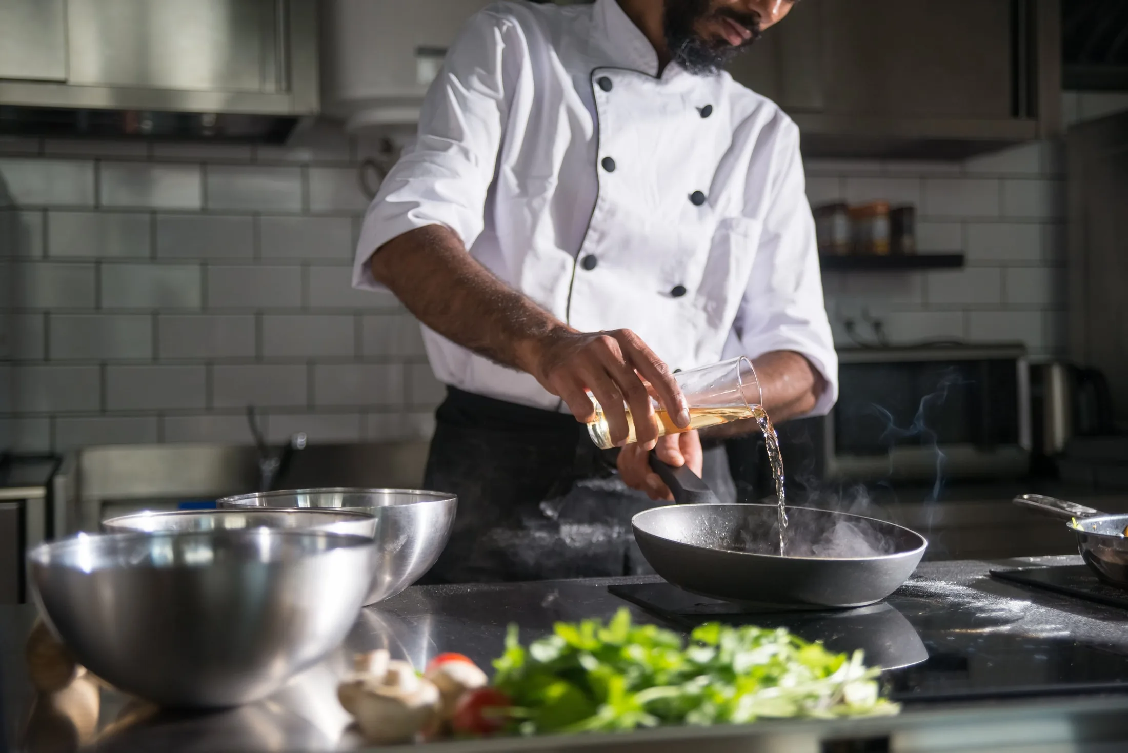 A chef carefully finishing a plated dish with fresh greens