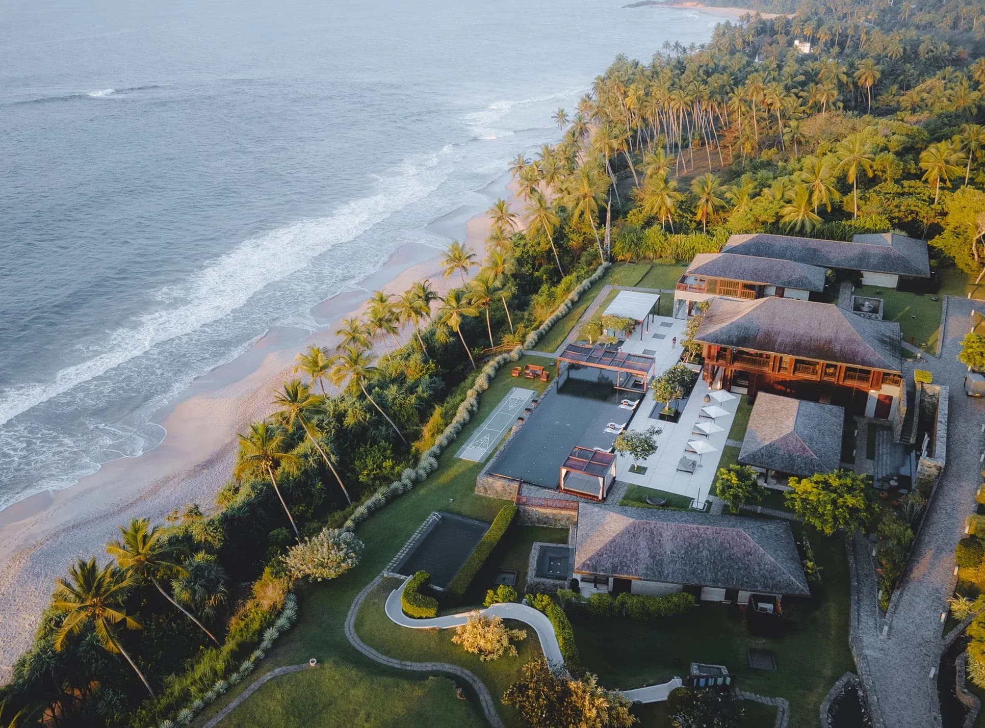 Aerial view of ÀNI Sri Lanka with a pool, coastal villas and palm-lined beach