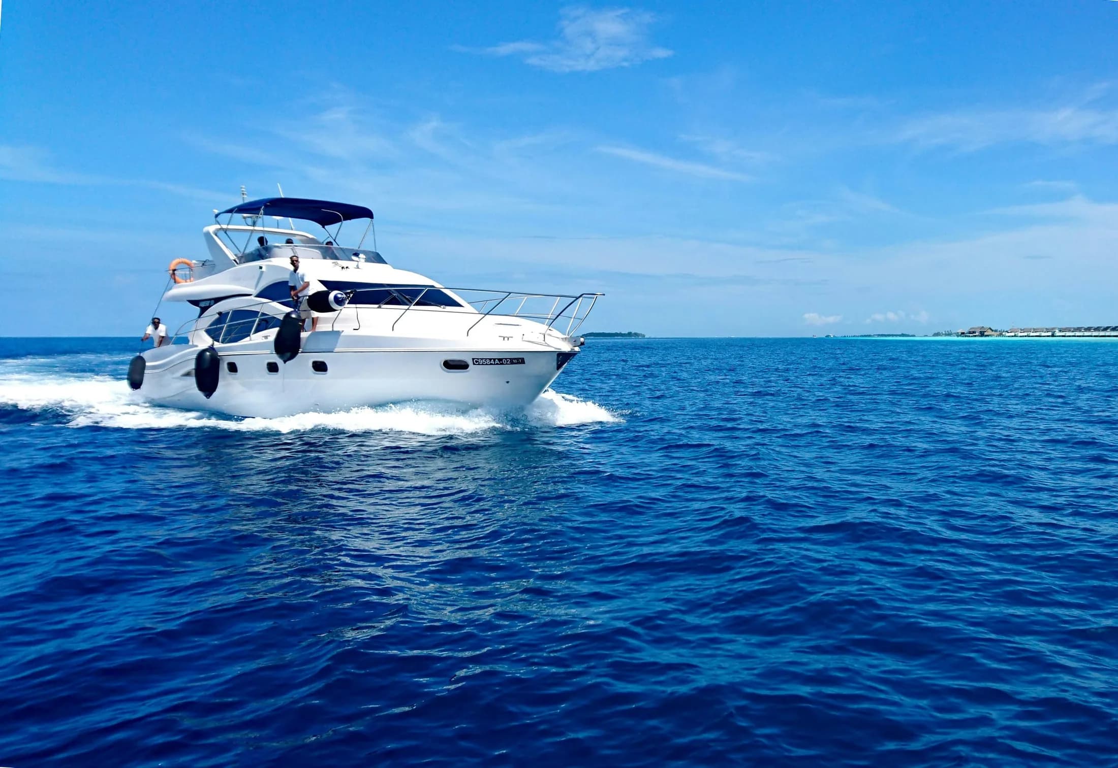 A white motor yacht on calm water beneath a peach-coloured sunset