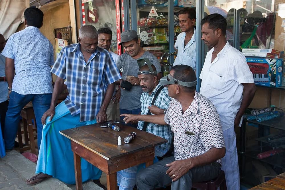 Gem merchants examining stones together at a trading table in Beruwala